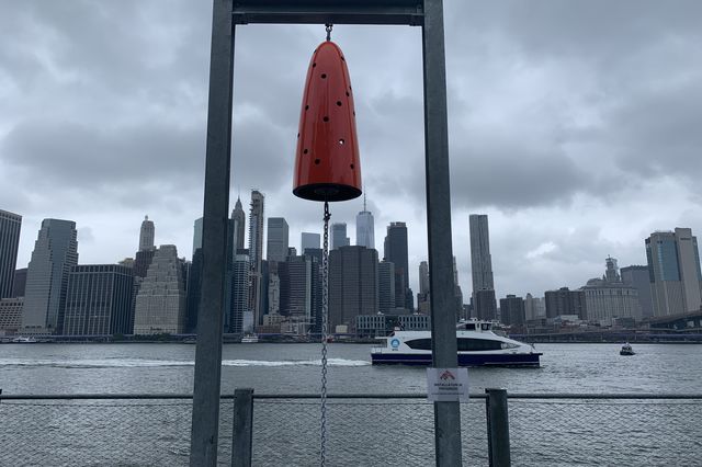 A public art project featuring a red bell on the waterfront in Brooklyn